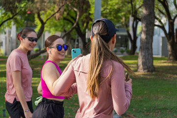 Three young Latina women smiling and taking a selfie together in park