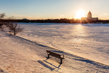 A bench is sitting in the snow next to a large building