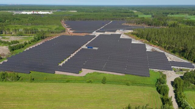 Aerial trucking pan across Solar Farm in Finland showcasing bifacial panels and clean energy, panoramic establishing overview