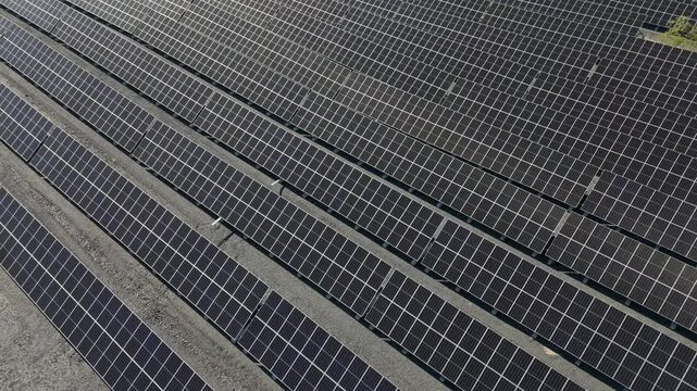 High angle aerial orbit of Solar Farm bifacial solar panels shining in the Finnish sunlight, orbit from angled to parallel