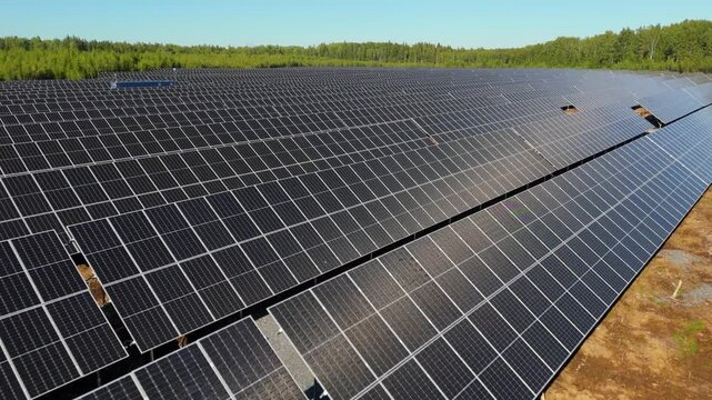 Smooth aerial angled dolly above bifacial solar panels at Solar Farm in Finland with sunlight reflections