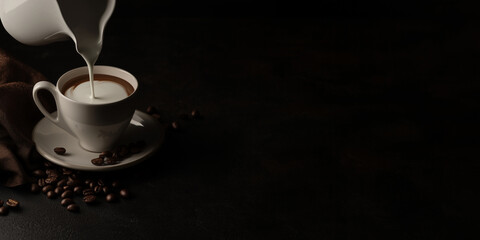 Obraz premium Pouring milk cream into a cup of coffee with coffee beans scattered beside it, isolated on a dark background with copy space