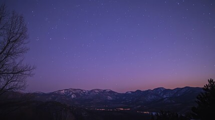 Fototapeta premium Majestic mountains silhouette under a starry sky at dusk, featuring a gradient of twilight colors and twinkling stars above.