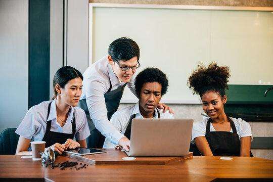 Diverse entrepreneurs in stylish coffee shop have a team meeting. Barista owner discuss work on laptop. Multiethnic employees successful teamwork business discussion. - Powered by Adobe