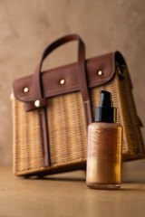 Summer still life with gold shimmer body lotion bottle and straw bag on beige background