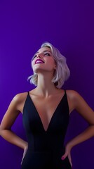Naklejka premium A young woman with platinum blonde hair, wearing a sleek black dress and standing with her hands on her hips, giving a confident smile, against a deep purple background.