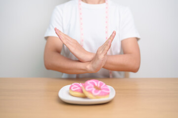 woman hand reject donut dessert, female refuse Unhealthy junk food. Dieting control, Weight loss, Obesity, eating lifestyle and nutrition concepts