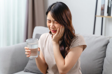 A woman is in pain and is holding her face having a toothache. Healthcare and medical concept.