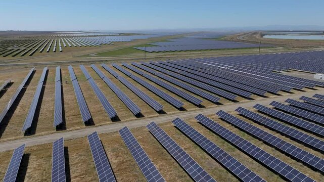 Aerial view of solar panel rows in a barren grass field