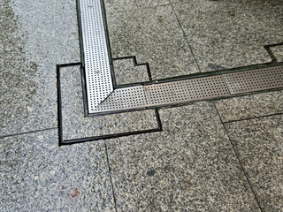 across the path there is a channel with a metal grid for drainage interlocking paving. the water is...