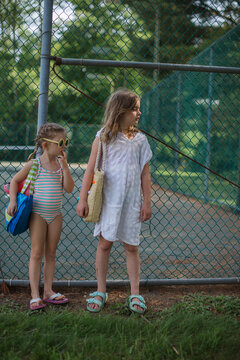 two sisters standing by tennis courts wearing pool clothes