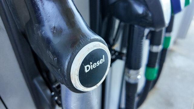 Close-up of a diesel pump nozzle at a gas station, highlighting fuel choices related to environmental impact and energy consumption