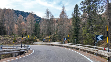 Scenic mountain road with sharp curve surrounded by autumn trees, illustrating the concept of...