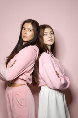 Stylish Young Women Pose Confidently in Matching Pastel Outfits Against a Soft Pink Backdrop