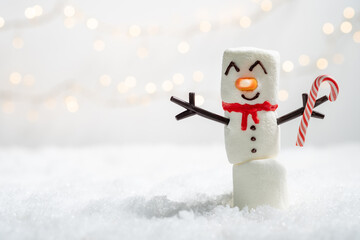 A snowman with a candy cane is standing in the snow