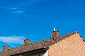 Brick house tiled roof with chimneys under a clear sky