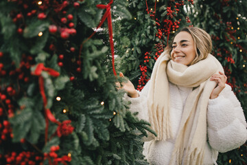 Young beautiful woman enjoying Christmas decorations on city street.