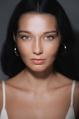 Obraz premium A close-up of a woman with flawless skin and an intense gaze, highlighting her radiant complexion and natural beauty. Perfect for beauty, skincare, and cosmetic product advertisements or tutorials.