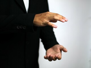 Fototapeta premium A confident hand in a sleek black suit gestures animatedly, illustrating a strategic business concept such as focus, collaboration, goal setting, time management, networking, emphasizing collaboration