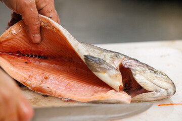 Preparing fresh salmon fillet with care in a modern kitchen setting during daylight hours