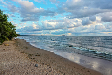 Serene beach walk during sunset near calm waters and scattered clouds in a tranquil coastal setting