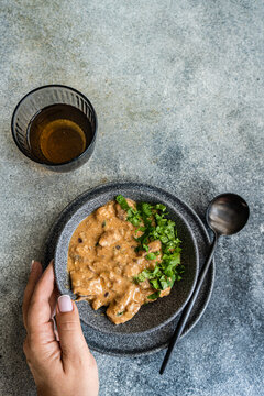 Overhead view of a bowl of beef stroganoff with fresh coriander and a glass of white wine