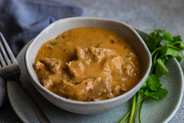 Close-up of a bowl of beef stroganoff with fresh coriander