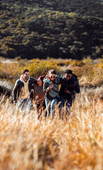 Smiling group of friends having fun while hiking together on hill.