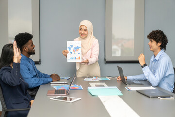 Muslim businesswoman in hijab presenting data charts and world map in a meeting, business presentation, professional teamwork, analysis, data driven strategy, diverse workplace, business communication