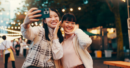 Happy, friends and Asian women with selfie in city at night market for fun, bonding and relax....