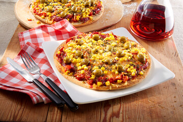 Pizza Olive Zwiebel Mais auf gedecktem TIsch mit karierter Serviette