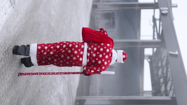 anta Claus dressed in a red robe, carrying a staff and bag, walks through a frosty industrial space. A cinematic contrast of tradition and modernity.