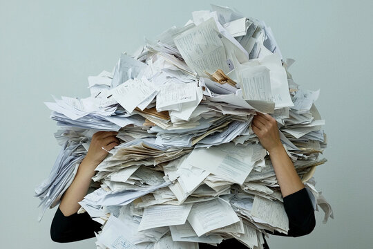 Overwhelmed individual buried under a pile of disorganized papers