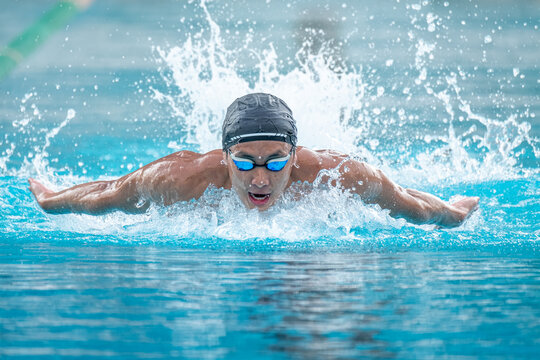 Close-up front view of a man swimming butterfly stroke in a swimming pool