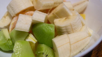 Banana, kiwi, mandarin sliced ​​in a deep plate. Fruit salad with yogurt
