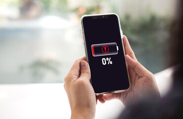 Close-up view of woman using mobile phone with battery died notification screen Zero percent...