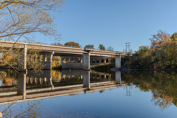 Fototapeta premium A bridge spans a river with a calm, reflective surface