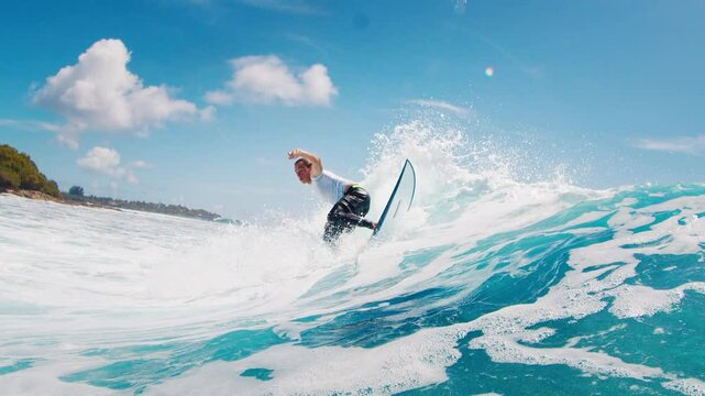Teen boy surfer rides the wave and makes sharp turn with spray. Tropical surfing in the Maldives