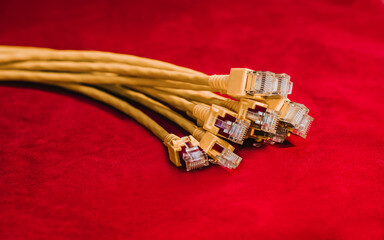 Yellow Ethernet network cable with RJ45 connector on a red background, representing internet...