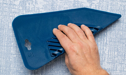 Applying a blue squeegee tool on a textured wall for effective cleaning and maintenance