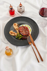 Braised Pork Steak with Parsnip Cream on a Black Plate