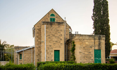 View of stone facade villa with green window and doors in the garden