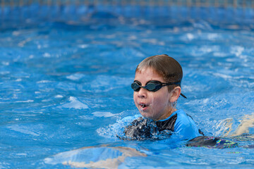 Close-up action portrait of a young swimmer while swimming breaststroke style in the swimming pool
