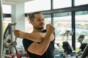 A handsome caucasian man in black shirt warm up before workout for weight training in sport gym.