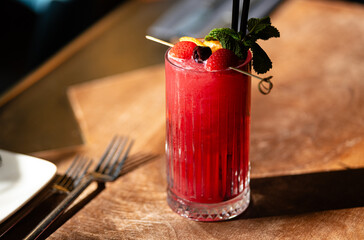 strawberry cocktail on a table with blackberry on a wooden table, with cutlery in a restaurant 
