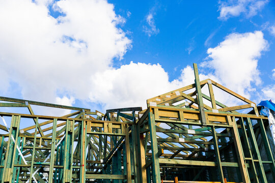town house getting built in front of blue sky with fluffy white clouds