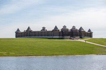 A large wooden building with a castle-like appearance sits on a hill overlooking