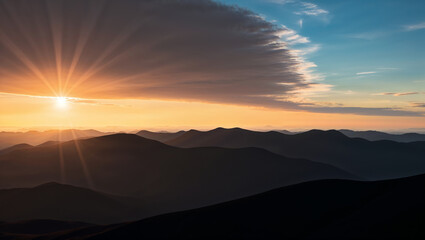Obraz premium Sunset over mountain peaks with dramatic sky and shadows.