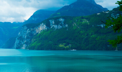 Vivid azure waters contrasting the rugged mountain backdrop creates a striking natural tableau,...