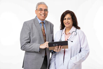 Portrait of smiling senior woman doctor standing with confident man with digital tablet